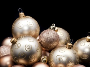 a black background with copyspace framed with a selection of glittery gold christmas ornaments